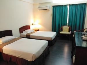 a hotel room with two beds and a table at Hotel Seri Malaysia Alor Setar in Alor Setar
