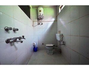 a bathroom with a toilet and a light on the wall at Anamika Hotel in Nainital