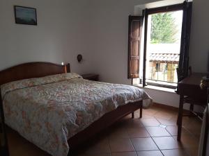 1 dormitorio con cama, ventana y escritorio en Giardino Donna Lavia, en Polizzi Generosa