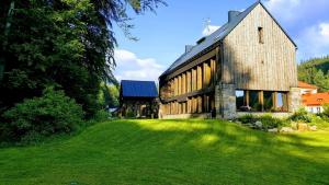 a large stone building with a grass yard at Krakonošova Dílna "WOODHAUS" in Špindlerův Mlýn