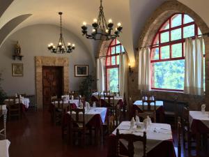 a dining room with tables and chairs and windows at MONASTERIO de SANTA MARÍA DE VALVANERA in Anguiano