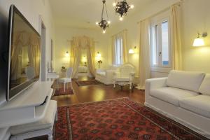 a living room with a white couch and a tv at Villa Las Tronas Hotel & SPA in Alghero