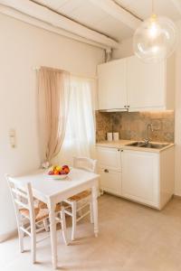 a white kitchen with a white table and chairs at Romantic house Priotissa II in Tympáki