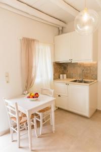 biała kuchnia z białym stołem i krzesłami w obiekcie Romantic house Priotissa II w mieście Tympáki