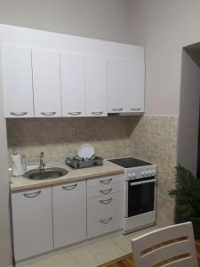 eine Küche mit weißen Schränken, einer Spüle und einem Herd in der Unterkunft Stankovic Apartman in Vranje
