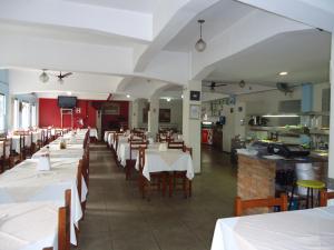 a restaurant with white tables and chairs and a kitchen at Hotel Turista in Belo Horizonte