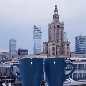 ワルシャワにあるDELUXE WIDOK 24 APARTMENTの窓辺に座る青いコーヒーカップ2つ