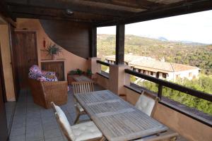 eine Veranda mit einem Holztisch und Stühlen auf dem Balkon in der Unterkunft Le stelle di Portisco in Marina di Portisco