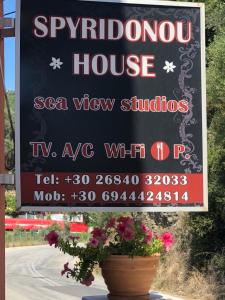 Una señal para una casa de espías con flores en una olla en Spyridonou House en Parga
