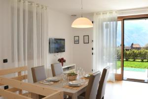 comedor con mesa, sillas y TV en Apartment Gli Ulivi - Tremezzina, en Tremezzo