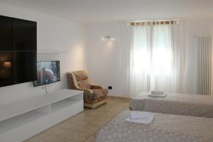a hotel room with a bed and a tv and a chair at Apartment Gli Ulivi - Tremezzina in Tremezzo