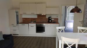 a kitchen with white cabinets and a kitchen table at Ferienwohnung Böttcher in Putbus