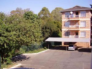 un bâtiment avec une voiture garée sur un parking dans l'établissement Town View, à Pietermaritzburg