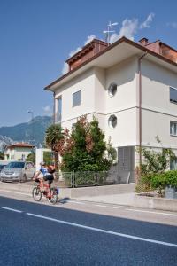 una persona in bicicletta lungo una strada accanto a un edificio di Casa Rosa dei Venti a Torbole