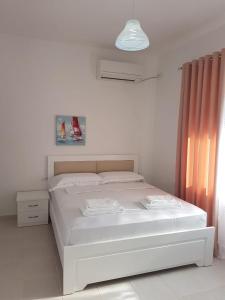 a white bed in a white room with a window at Vila Alikaj in Sarandë