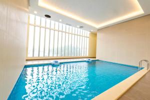 a swimming pool in a room with a large window at Sedra Residence in Kuwait