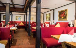 a dining room with red chairs and tables at Wennhof in Scharbeutz
