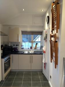 a kitchen with white cabinets and a sink and a window at The Cwtch in Cardiff