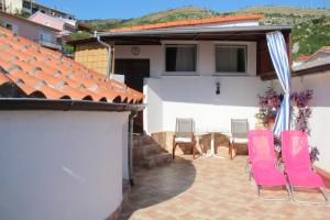 een patio met stoelen en een parasol en een huis bij Guesthouse Donko 1 & 2 in Senj