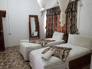 a room with two beds and a mirror at Paloma Guest House in Kenema