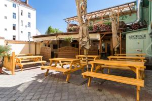 un grupo de mesas de picnic de madera frente a un edificio en Pension Akat, en Praga