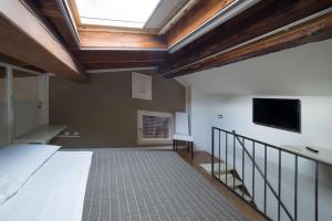 フェラーラにあるAlkimia Smart Roomsのベッド1台と壁掛けテレビが備わる客室です。