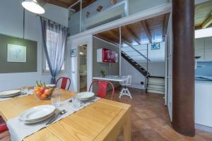 ein Esszimmer mit einem Tisch und einer Treppe in der Unterkunft Alkimia Smart Rooms in Ferrara