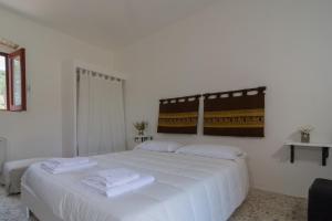 1 dormitorio con 1 cama blanca grande y toallas. en Agriturismo di Serragiumenta, en Altomonte