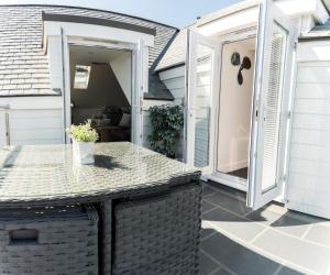 un patio con una mesa y una puerta abierta en The Lighthouse Penthouse, Studio and Holiday Home en St Ives