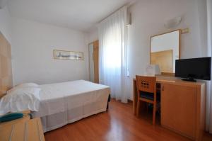 Hotel Igea في بادوفا: غرفة نوم بسرير ومكتب مع تلفزيون