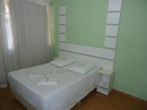 a white bed sitting next to a white wall at Hotel Turista in Belo Horizonte