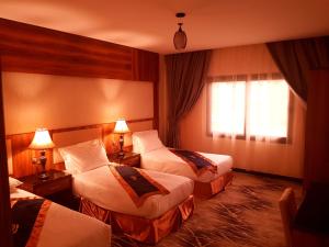 a hotel room with three beds and a window at Azd Hotel in Abha