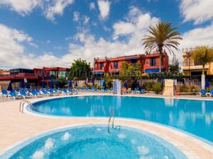 a swimming pool at a resort with chairs and a building at Villa Feliz 128 in Meloneras