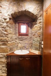 uma casa de banho com um lavatório e uma parede de pedra em Cottage House in Traditional Greek Village em Kanália