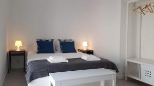 um quarto branco com uma cama grande e almofadas azuis em 5 Rua Antão Girão em Setúbal