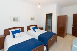 a bedroom with two beds with blue and white sheets at AtJuditehome in Alpiarça