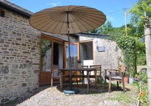 eine Terrasse mit einem Tisch und einem Sonnenschirm in der Unterkunft Raleigh Barn in West Putford