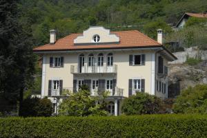 a large white house with a red roof at B&B Le Camelie in Domodossola