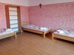 three beds in a room with pink walls and wooden floors at Penzion U Paroháče in Prostějov