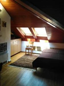 a attic room with a bed and a chair in it at Miha Apartman in Subotica
