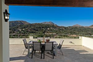 a table and chairs on a patio with a view of mountains at Aliki Serenity Cottage in Mixórrouma