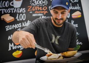 a man eating a plate of food with a fork and knife at Ohana Tarifa Hostel in Tarifa