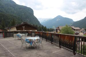 two tables and chairs on a balcony with mountains at Garni Hirsch in Canazei