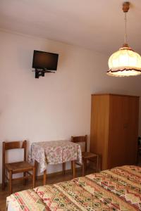a bedroom with two beds and a table and a tv at Garni Hirsch in Canazei