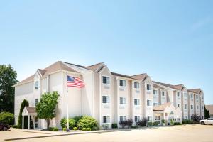 ein großes weißes Gebäude mit amerikanischer Flagge in der Unterkunft Microtel Inn & Suites by Wyndham Springfield in Springfield