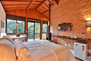 a bedroom with a large bed and a brick wall at Chalés Cinco Estrelas in Monte Verde