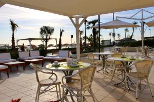 un patio al aire libre con mesas, sillas y sombrillas en Hotel Caravel, en Marotta