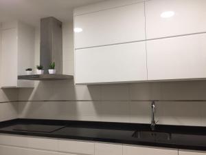 kuchnia z białymi szafkami i zlewem w obiekcie Apartamento Lujo, Primera linea playa, Garaje, Wifi, Piscina climatizada w mieście Roquetas de Mar
