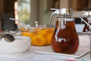 a bottle of honey on a table with a bowl of oranges at Riviera Perdika Hotel in Perdika