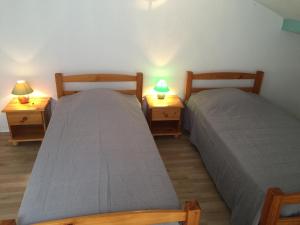 ビスカロッス・プラージュにあるMaison Indigo 6 personnesのベッド2台(ナイトスタンドにランプ2つ付)が備わる客室です。